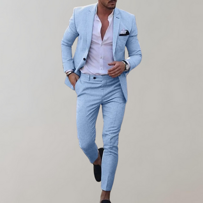 Mann in hellblauem Anzug mit weißem Hemd und schwarzem Einstecktuch, modisch gekleidet, läuft vor grauem Hintergrund. Elegante Herrenmode.