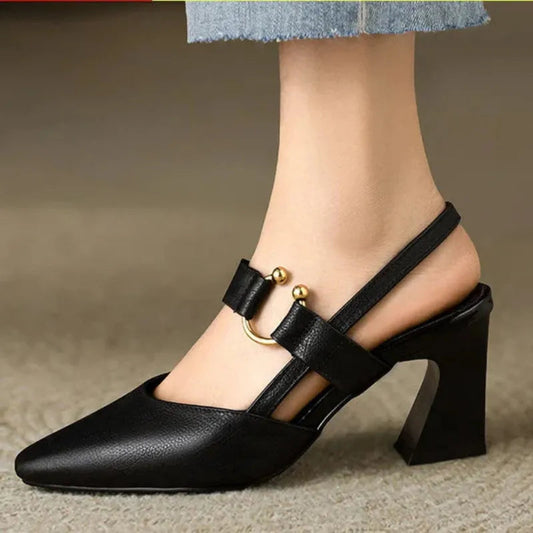 Schwarzer Damenpumps mit Blockabsatz und goldenen Verzierungen, elegantes Design, ideal für modische Anlässe, getragen mit blauer Jeans.