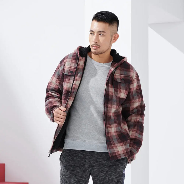Mann in kariertem Flanellhemd mit Kapuze, grauem T-Shirt und Jogginghose. Modetrend, lässiger Herrenstil, Herbstmode.