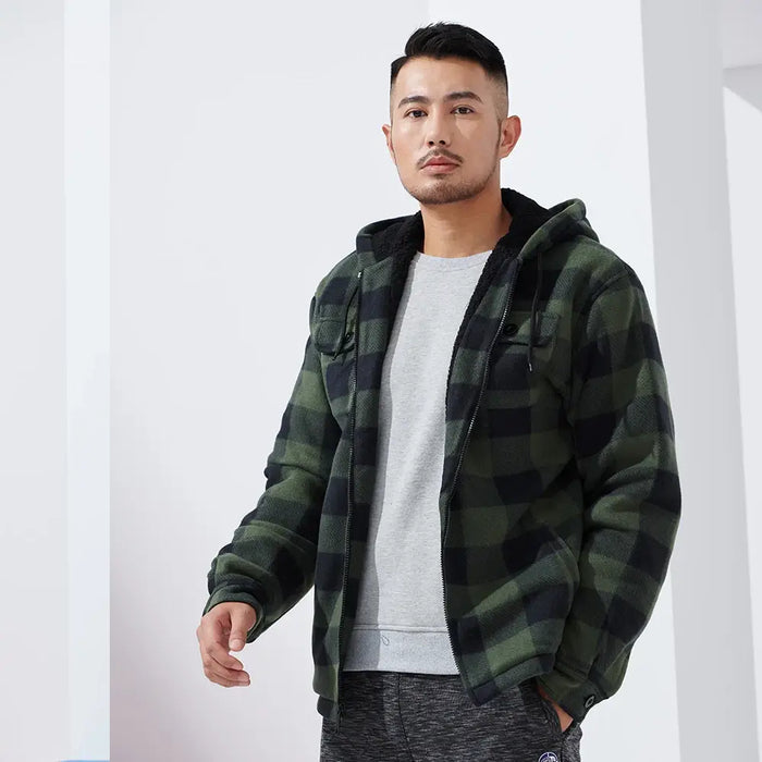 Mann in grün-schwarz karierter Jacke mit Kapuze, grauem Pullover und grauer Hose. Modetrend, Herrenmode, lässiger Stil, Winterbekleidung.