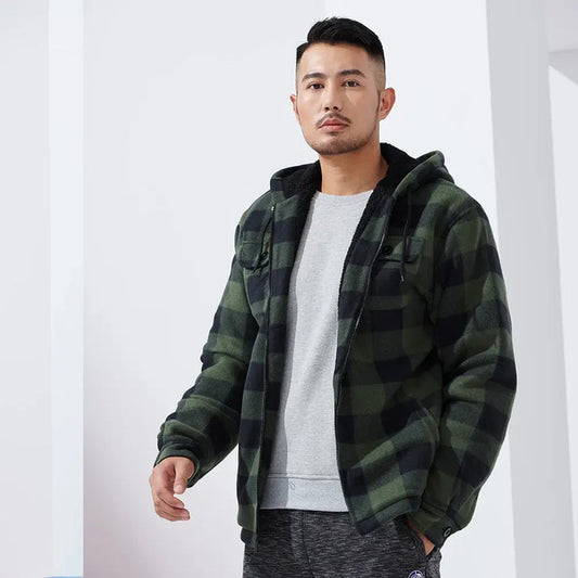 Mann in grün-schwarz karierter Jacke mit Kapuze, grauem Pullover und grauer Hose. Modetrend, Herrenmode, lässiger Stil, Winterbekleidung.