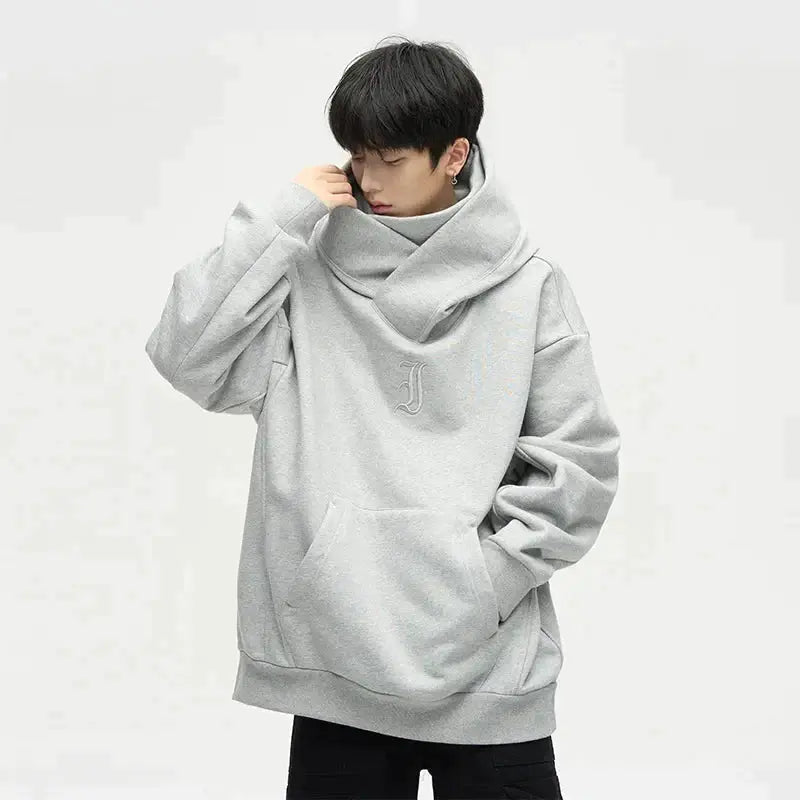 Junger Mann in grauem Oversize-Hoodie mit Kapuze und Kängurutasche, modisches Streetwear-Outfit, lässiger Stil, isolierter Hintergrund.