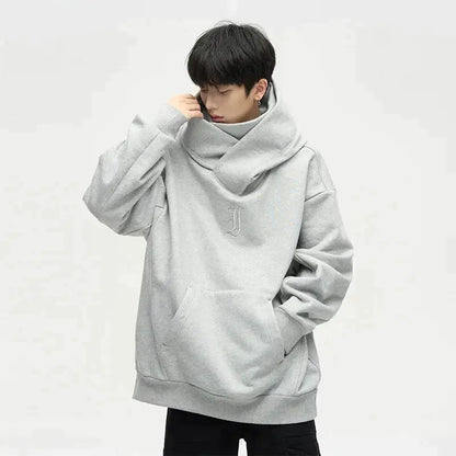 Junger Mann in grauem Oversize-Hoodie mit Kapuze und Kängurutasche, modisches Streetwear-Outfit, lässiger Stil, isolierter Hintergrund.