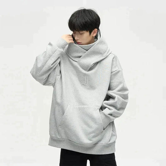 Junger Mann in grauem Oversize-Hoodie mit Kapuze und Kängurutasche, modisches Streetwear-Outfit, lässiger Stil, isolierter Hintergrund.
