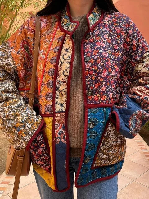 Bunte Patchwork-Jacke mit floralen Mustern, getragen von einer Person. Herbstmode, Boho-Stil, Vintage-Look, auffällige Farben, modisches Statement.