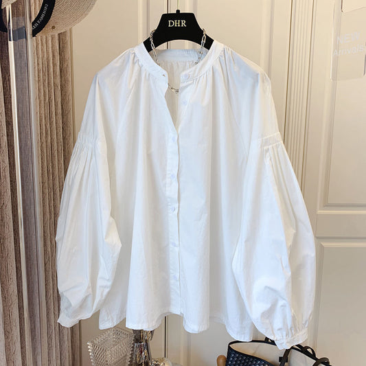 Weiße Bluse mit Puffärmeln, hängend auf einem Kleiderbügel. Modetrend, Damenbekleidung, elegantes Design, vielseitig kombinierbar.