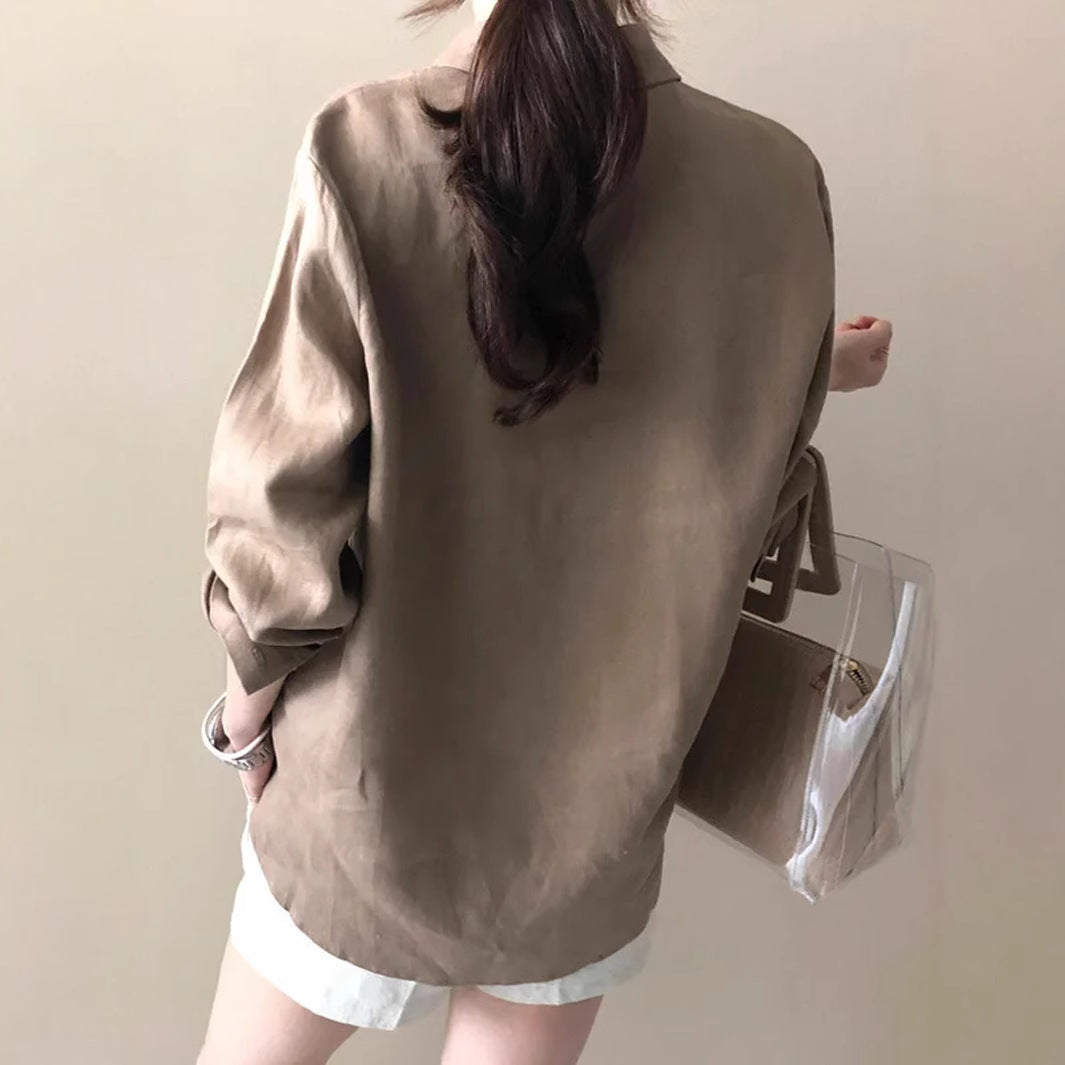 Frau in beiger Bluse und weißer Shorts, hält transparente Handtasche. Modetrend, lässiger Stil, Sommeroutfit, Damenmode, elegantes Design.