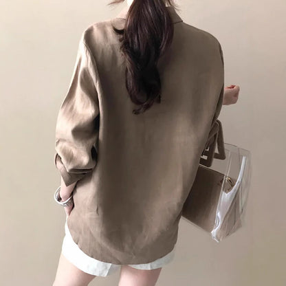 Frau in beiger Bluse und weißer Shorts, hält transparente Handtasche. Modetrend, lässiger Stil, Sommeroutfit, Damenmode, elegantes Design.
