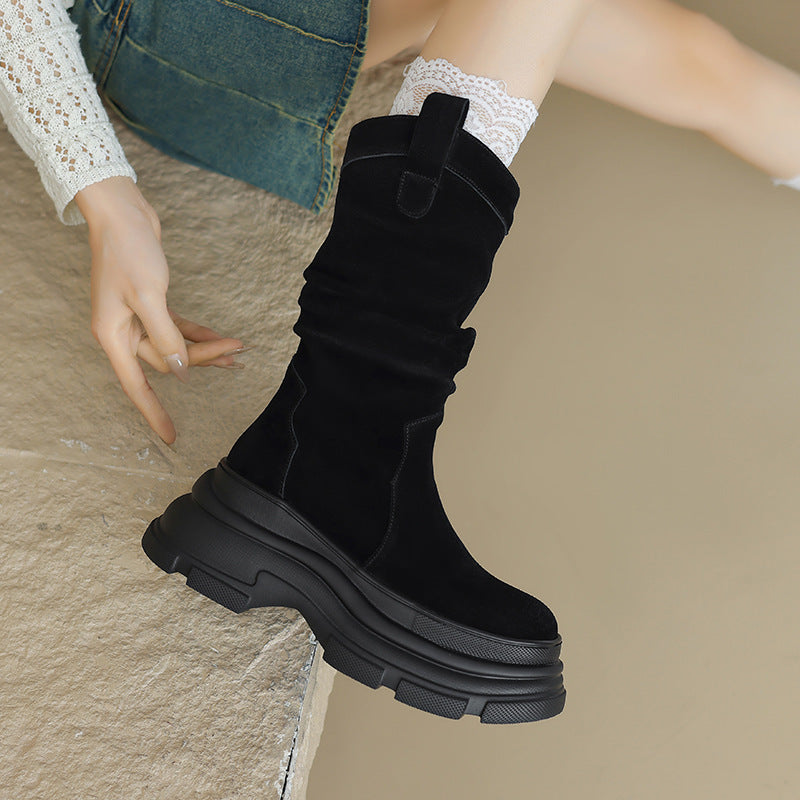 Schwarzer Damenstiefel mit dicker Sohle, getragen mit weißer Spitzenstrumpf, auf beigem Hintergrund. Modischer Herbst-Winter-Schuhtrend.