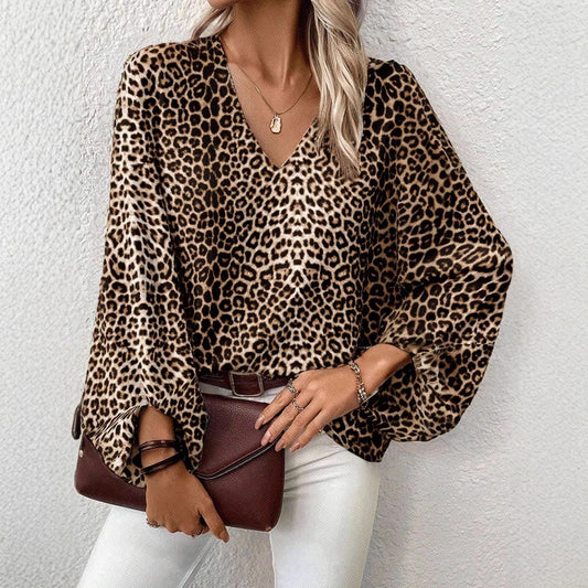 Frau in Leopardenbluse mit V-Ausschnitt, hält braune Handtasche, trägt weiße Hose. Modetrend, Damenmode, eleganter Look, Streetstyle.