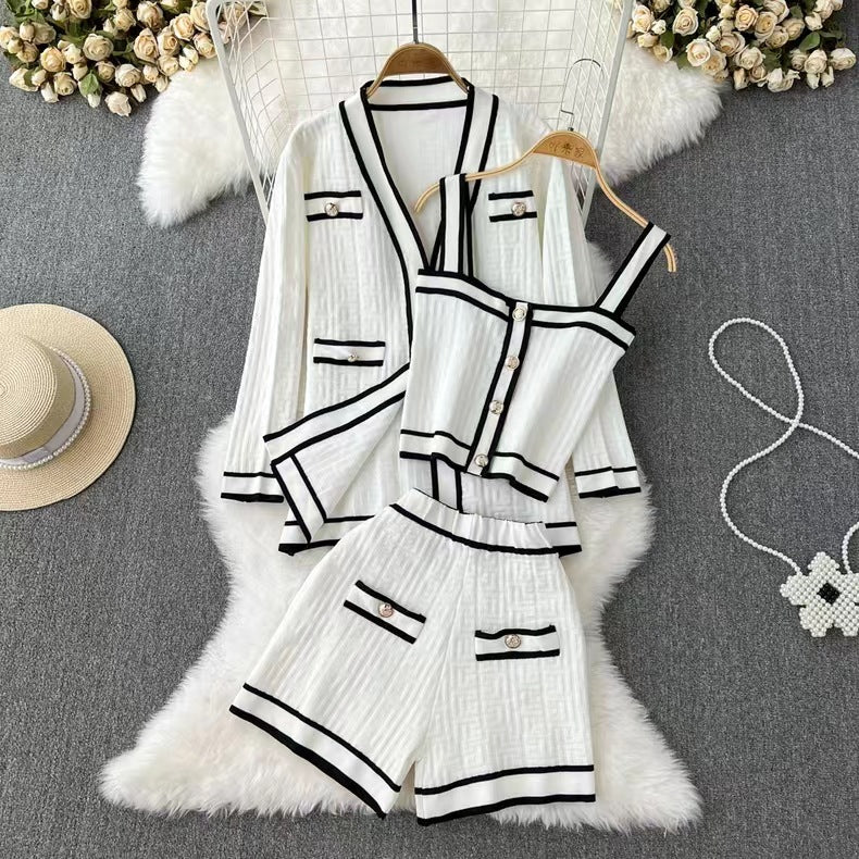 Damen Sommeranzug Set: Weißes, gestreiftes Top, Shorts und Jacke mit schwarzen Akzenten, elegant und modisch, auf grauem Hintergrund mit Blumen.