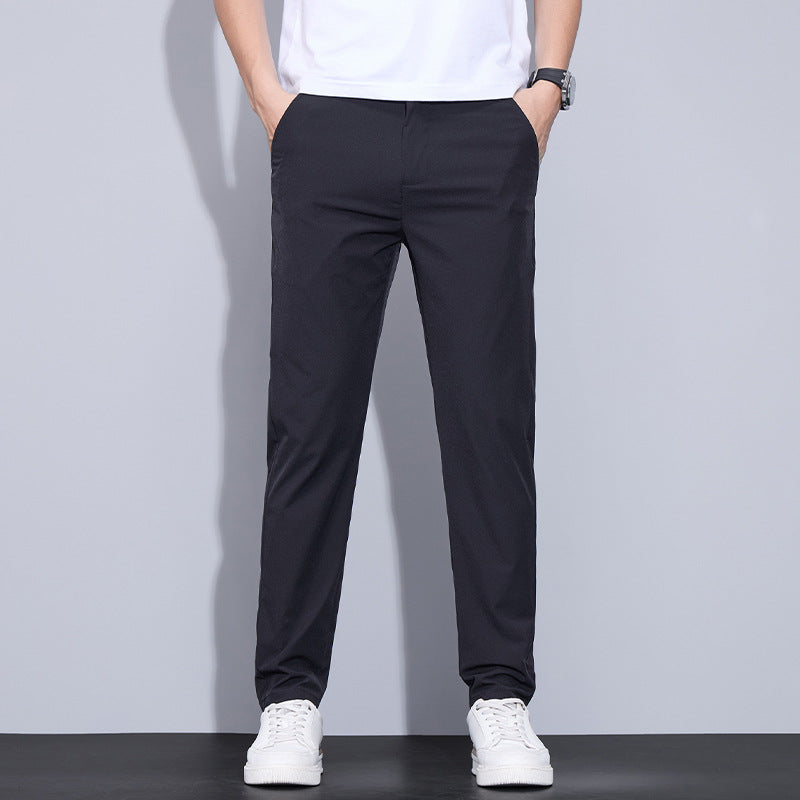 Mann trägt schwarze Chinohose und weiße Sneaker, lässiger Stil, moderne Herrenmode, ideal für Freizeit und Alltag, vor grauem Hintergrund.