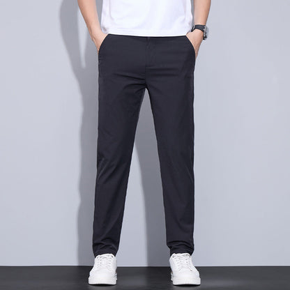 Mann trägt schwarze Chinohose und weiße Sneaker, lässiger Stil, moderne Herrenmode, ideal für Freizeit und Alltag, vor grauem Hintergrund.