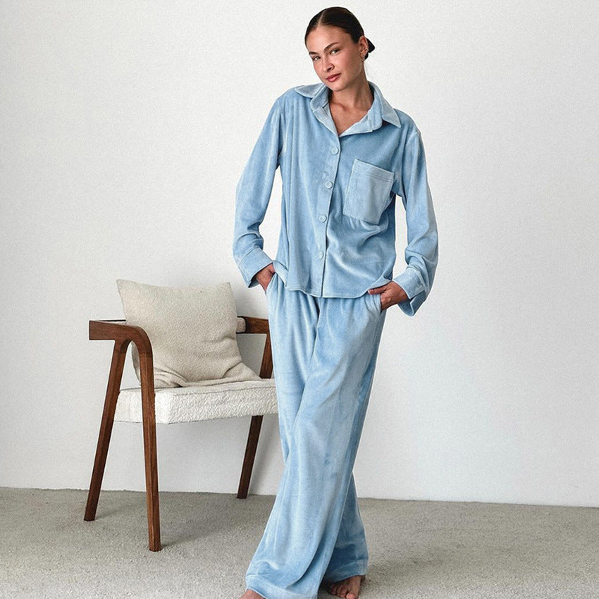 Frau in hellblauem Pyjama steht neben einem modernen Holzstuhl mit Kissen, minimalistische Einrichtung, gemütliche Nachtwäsche, entspannte Atmosphäre.