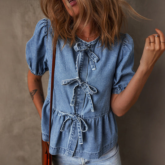 Frau in blauer Jeansbluse mit Schleifen, lässiger Stil, modisches Outfit, Sommermode, blonde Haare, grauer Hintergrund.