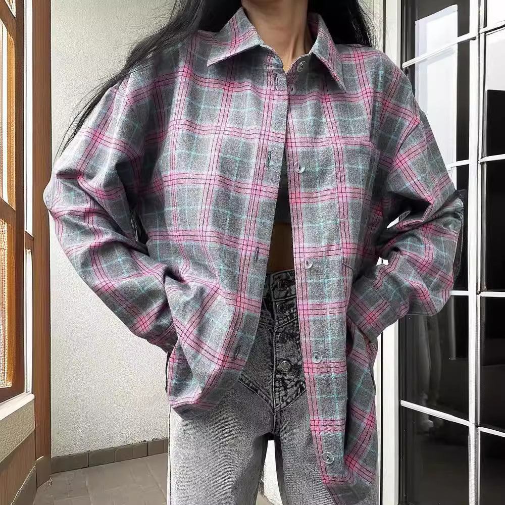 Frau in kariertem Hemd, graue und rosa Töne, kombiniert mit grauen Jeans, steht auf einem Balkon. Modetrend, lässiger Stil, Herbstmode.