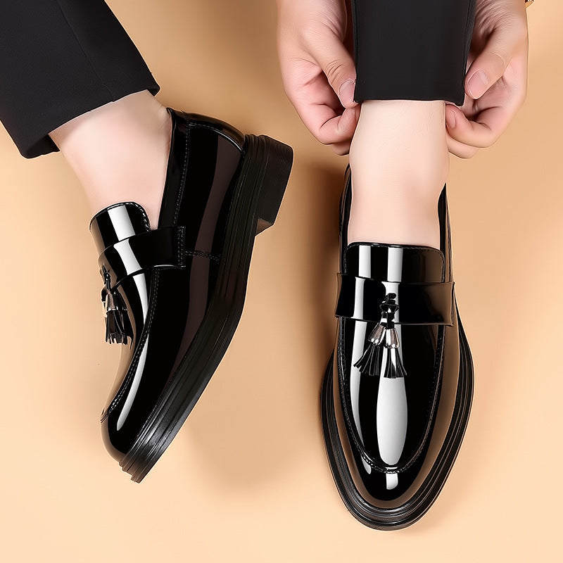 Schwarze Lackleder-Loafer mit Quasten, elegantes Design, getragen von einer Person auf beigem Hintergrund. Hochwertige Herrenschuhe, modisch und stilvoll.