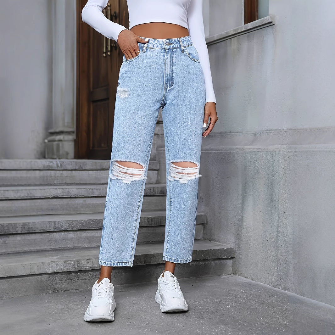 Frau in zerrissener Jeans und weißem Crop-Top auf Treppe. Modetrend, lässiger Streetstyle, weiße Sneaker, urbaner Look.