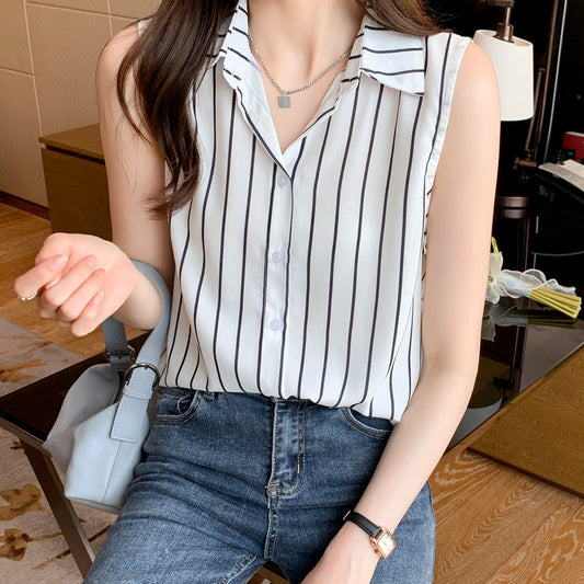 Frau in gestreifter Bluse und Jeans sitzt, hält eine graue Handtasche. Modernes, lässiges Outfit, ideal für Büro oder Freizeit.