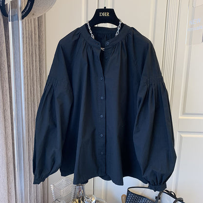 Schwarze Bluse mit Puffärmeln auf Kleiderbügel, elegante Damenmode, klassische Knopfleiste, stilvolles Design, hochwertige Stoffqualität.