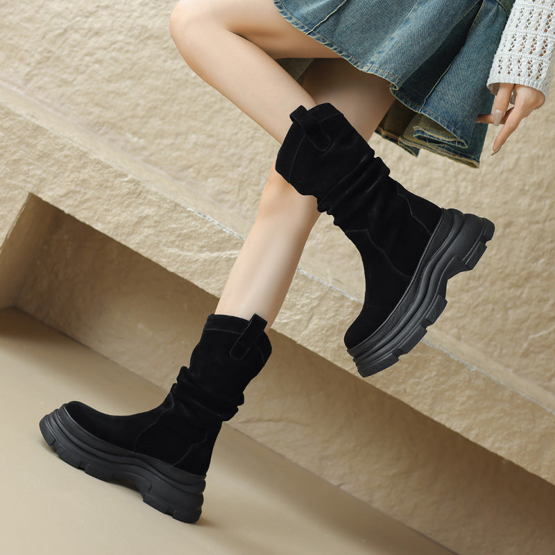 Schwarze Damenstiefel mit dicker Sohle, getragen von einer Person in Jeansrock. Modische Herbst-Winter-Schuhe, ideal für trendige Outfits.