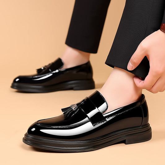 Schwarze Lackleder-Loafer mit Quasten, getragen von einer Person in schwarzer Hose. Elegante Herrenschuhe, ideal für formelle Anlässe.