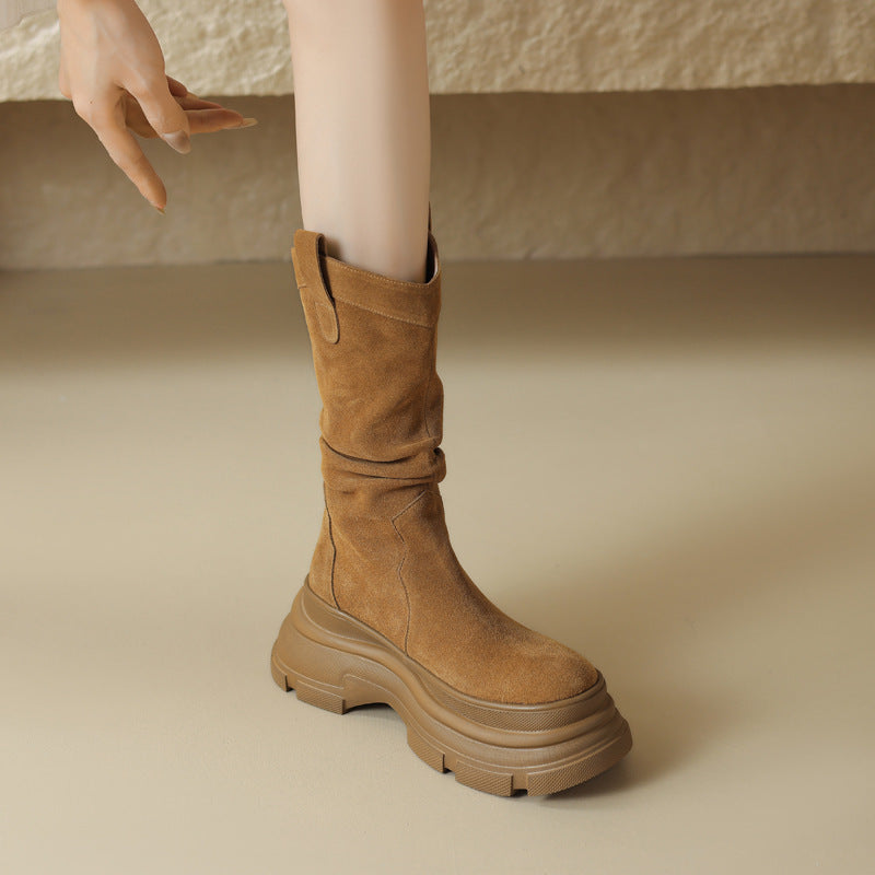 Beige Damenstiefel mit dicker Sohle, aus Wildleder, auf beigem Hintergrund. Modischer Herbst-Winter-Schuh, ideal für trendige Outfits.