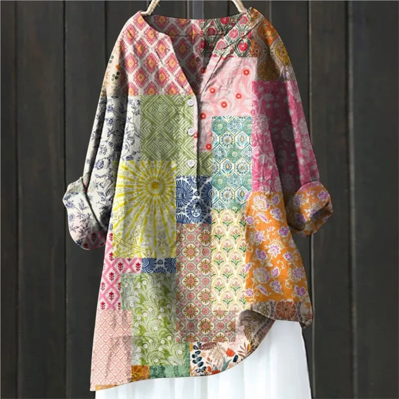 Bunte Patchwork-Bluse mit langen Ärmeln, geometrischen und floralen Mustern, hängend vor dunklem Holzhintergrund. Boho-Stil, modisch, einzigartig.