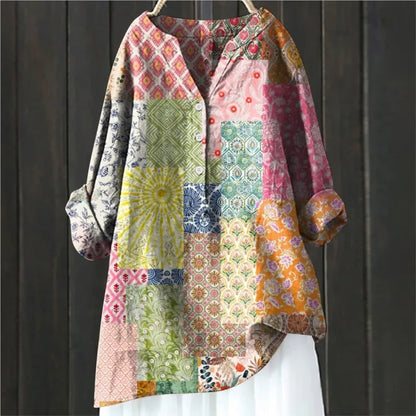 Bunte Patchwork-Bluse mit langen Ärmeln, geometrischen und floralen Mustern, hängend vor dunklem Holzhintergrund. Boho-Stil, modisch, einzigartig.