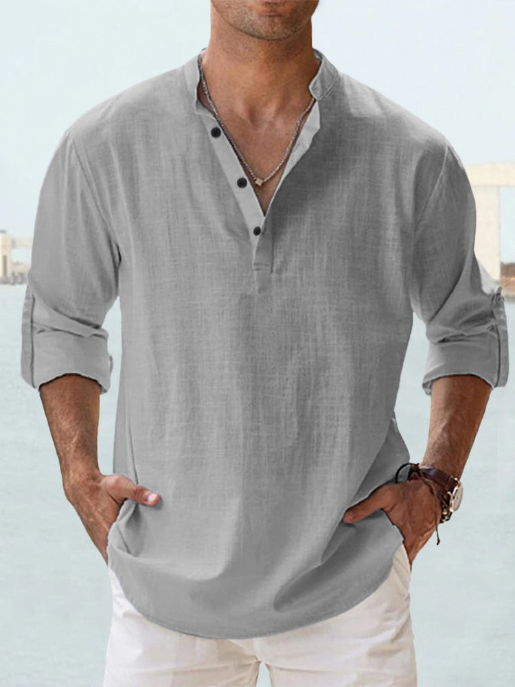 Graues Herrenhemd mit Stehkragen und Knopfleiste, lässig hochgekrempelte Ärmel, kombiniert mit weißer Hose. Ideal für Sommermode und Freizeitlook.