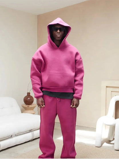 Person in pinkem Hoodie und Jogginghose steht in modernem Wohnzimmer. Modetrend, lässiger Stil, bequeme Kleidung, urbaner Look.