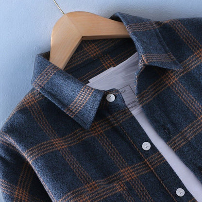 Dunkelblaues kariertes Flanellhemd auf Holzkleiderbügel, Nahaufnahme. Modetrend, Herrenbekleidung, Herbstmode, stilvolles Design.