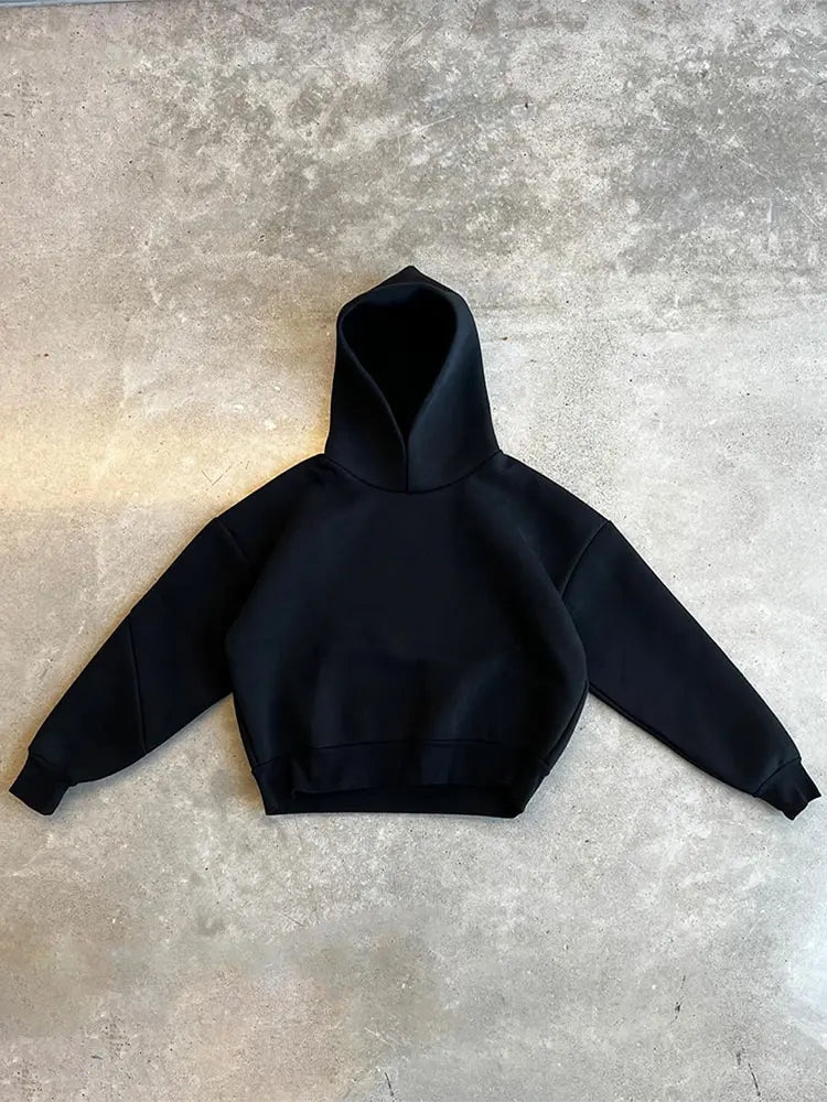 Schwarzer Hoodie auf Betonboden, minimalistisch und modern. Perfekt für Streetwear, Unisex-Mode, lässiger Stil. Ideal für Herbst und Winter.