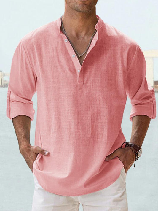 Mann in rosa Leinenhemd mit Stehkragen und Knopfleiste, lässig hochgekrempelte Ärmel, kombiniert mit weißer Hose. Ideal für Sommermode.