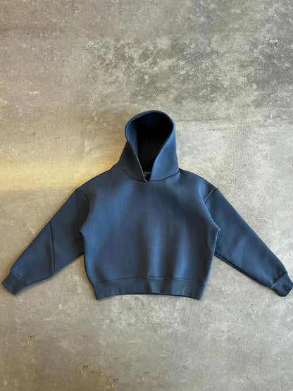 Dunkelblauer Kapuzenpullover auf grauem Betonboden, minimalistisch, modisch, Streetwear, Unisex-Hoodie, lässiger Stil, Herbstmode.