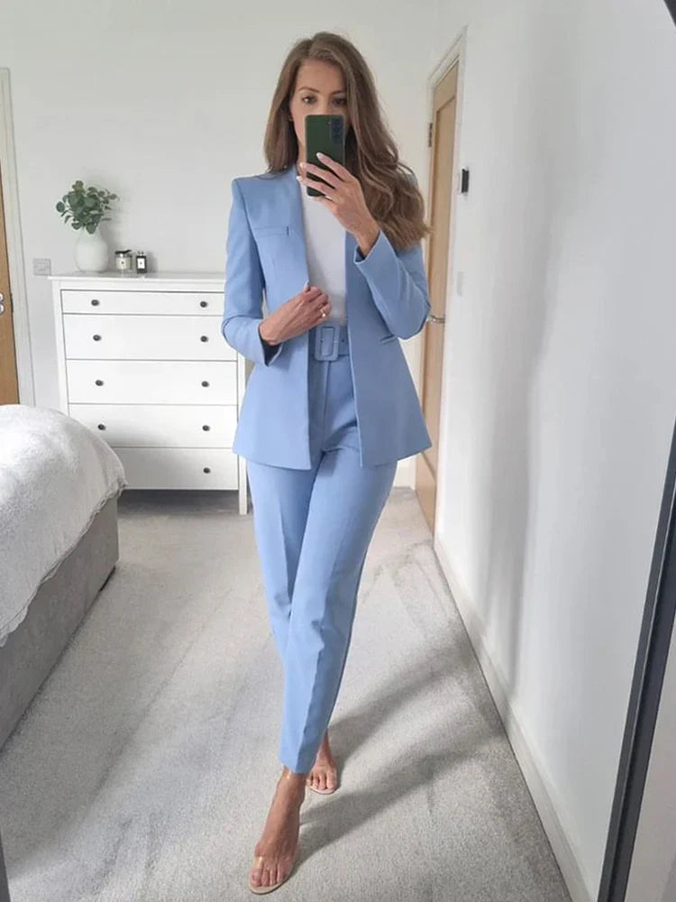 Frau im blauen Hosenanzug macht Selfie im Schlafzimmer, moderne Einrichtung, weiße Kommode, eleganter Business-Look, Mode, Damenbekleidung.