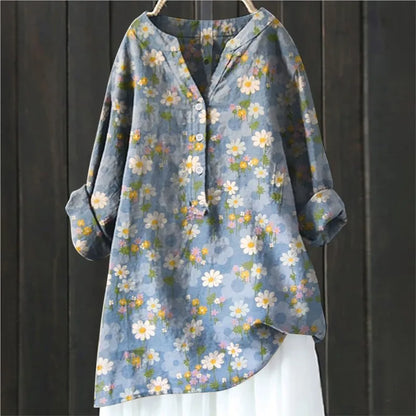 Blaues Damenhemd mit Blumenmuster, langen Ärmeln und Knopfleiste, hängend vor dunklem Holzhintergrund. Modetrend, Frühlingsmode, Damenbekleidung.