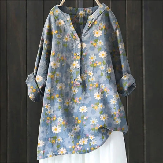 Blaues Damenhemd mit Blumenmuster, langen Ärmeln und Knopfleiste, hängend vor dunklem Holzhintergrund. Modetrend, Frühlingsmode, Damenbekleidung.