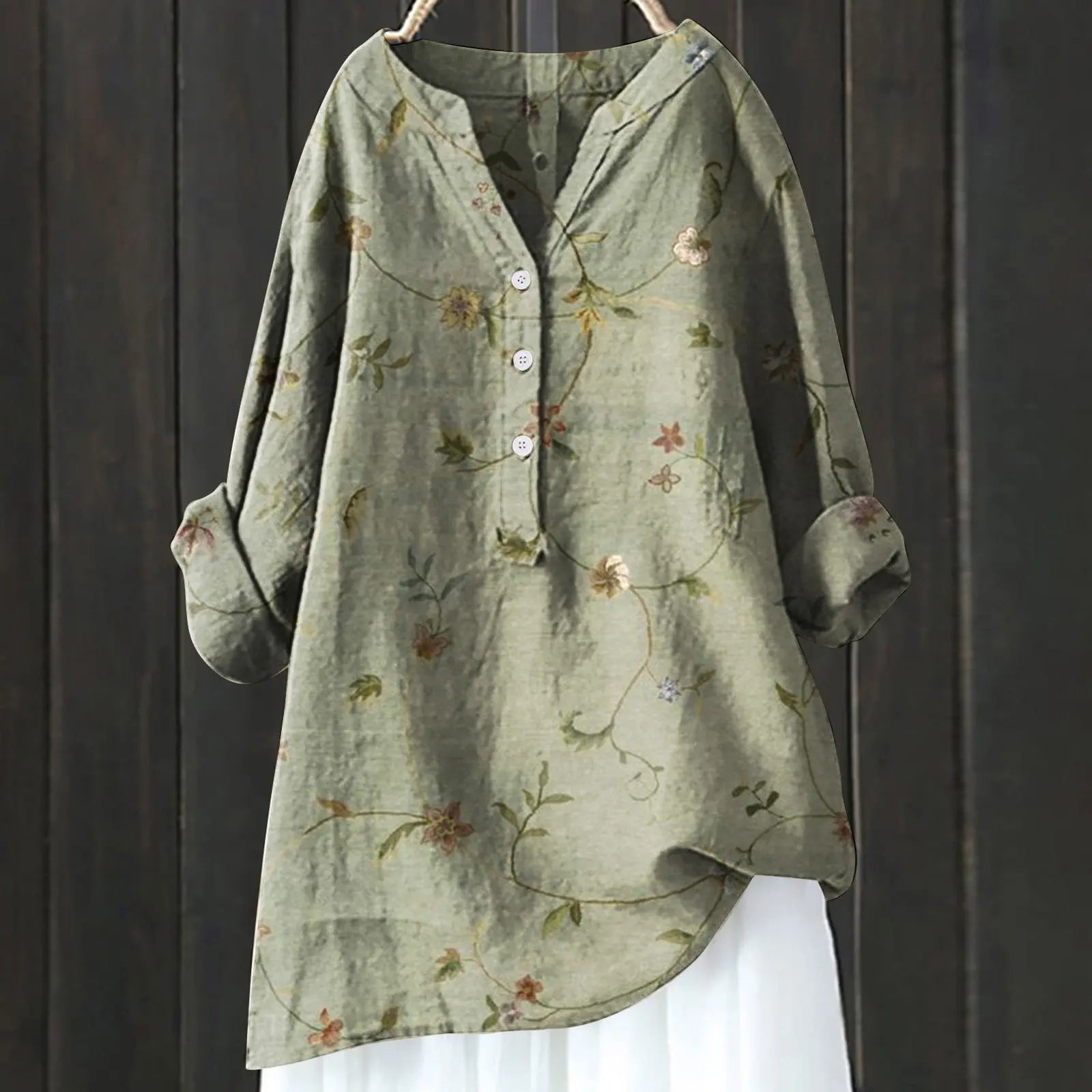 Grüne Leinenbluse mit Blumenmuster, Knopfleiste und langen Ärmeln vor dunklem Holzhintergrund. Damenmode, lässiger Stil, Herbstkleidung.