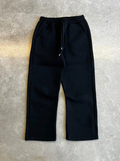 Schwarze Jogginghose aus Baumwolle auf grauem Hintergrund, elastischer Bund mit Kordelzug, seitliche Taschen, bequeme Freizeitmode.
