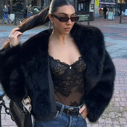 Frau in schwarzem Spitzen-Body, Pelzjacke und Sonnenbrille, hält Pferdeschwanz. Modetrend, Streetstyle, elegante Damenmode.