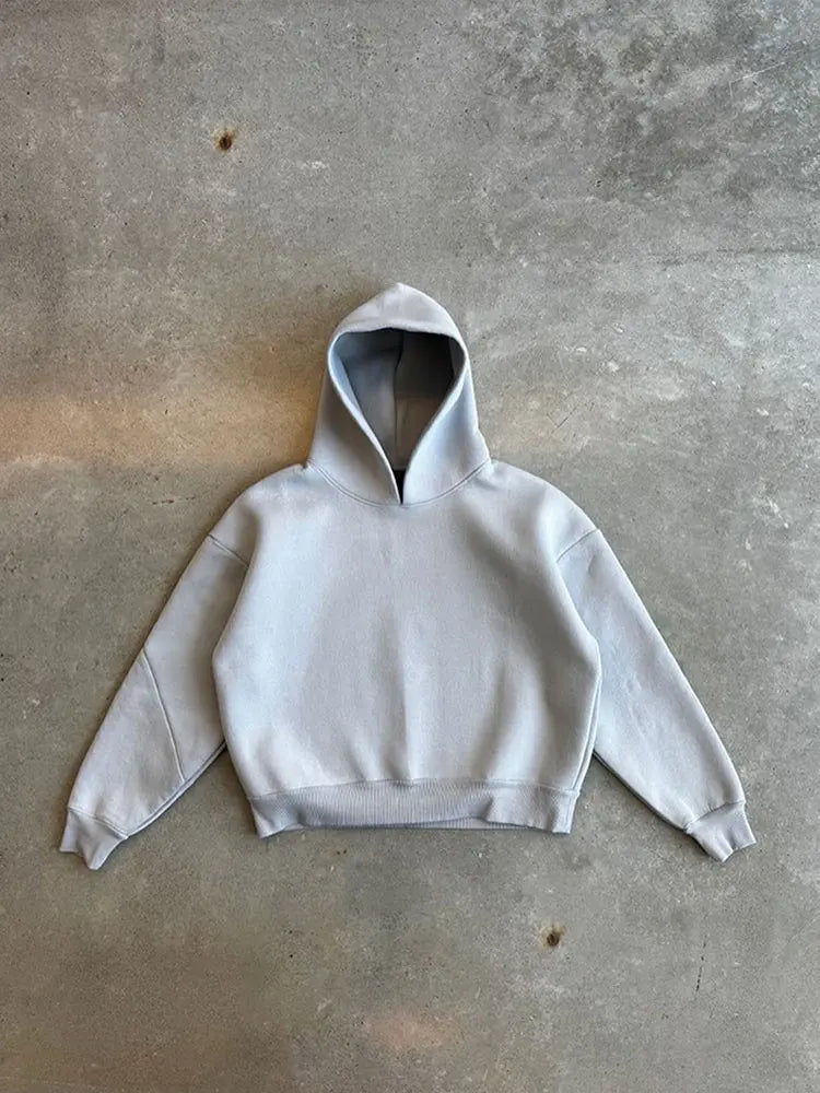 Grauer Kapuzenpullover auf Betonboden, minimalistisch, lässiger Stil, Mode, Streetwear, Unisex Hoodie, gemütlich, urbaner Look.