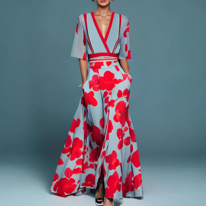 Frau in elegantem, bodenlangem Kleid mit roten Blumen auf blauem Hintergrund, V-Ausschnitt und kurzen Ärmeln. Modetrend, Abendmode, stilvolles Design.