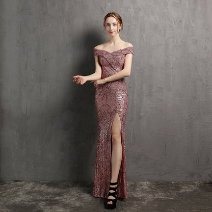 Frau in eleganter, schulterfreier Abendkleid mit Pailletten und hohem Schlitz, posiert vor grauer Wand. Perfekt für Gala oder Abendveranstaltung.