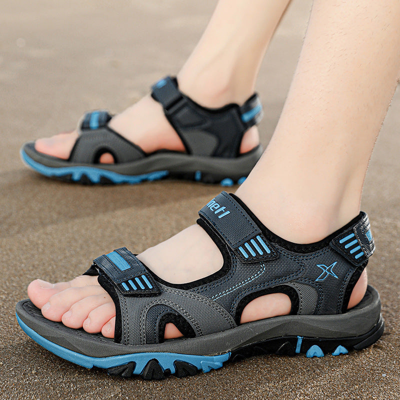 Graue Outdoor-Sandalen mit blauen Akzenten auf Sand. Bequeme, atmungsaktive Wandersandalen für Herren, ideal für Sommeraktivitäten und Trekking.