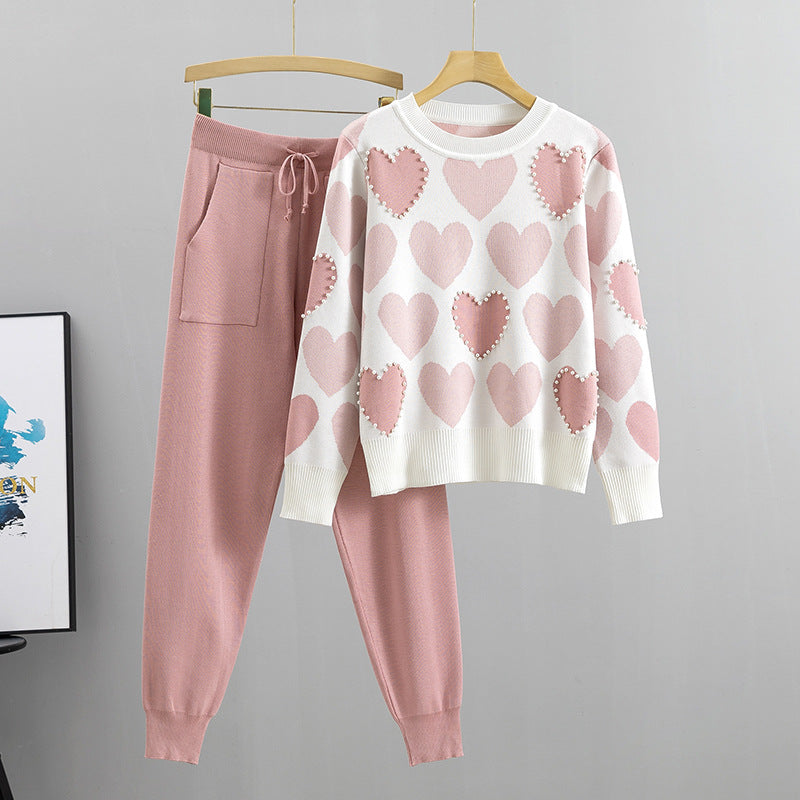 Rosa Damen-Loungewear-Set mit Herzmuster: Weißer Pullover mit rosa Herzen und passende rosa Jogginghose. Bequem, modisch, gemütlich.
