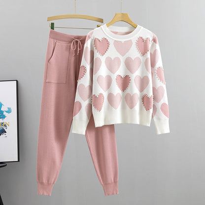 Rosa Damen-Loungewear-Set mit Herzmuster: Weißer Pullover mit rosa Herzen und passende rosa Jogginghose. Bequem, modisch, gemütlich.