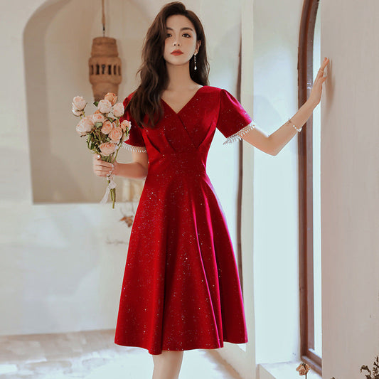 Frau in elegantem roten Kleid mit Blumenstrauß, steht in stilvollem Raum. Perfektes Outfit für Abendveranstaltungen oder Hochzeiten.