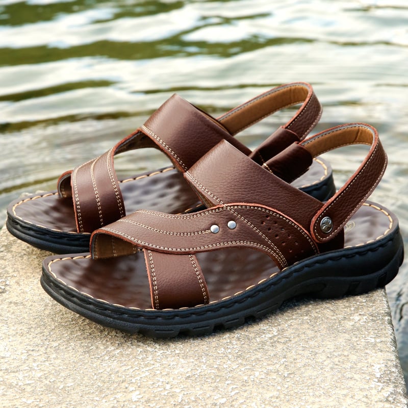 Braune Ledersandalen für Herren mit robusten Sohlen, ideal für Sommer und Outdoor-Aktivitäten, am Wasser platziert. Hochwertige Herrenschuhe.