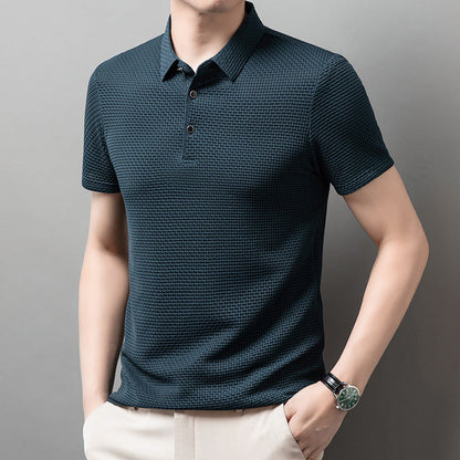 Mann trägt dunkelblaues Polohemd mit Strukturmuster, kombiniert mit beiger Hose. Elegante Herrenmode, modernes Design, Freizeitkleidung.